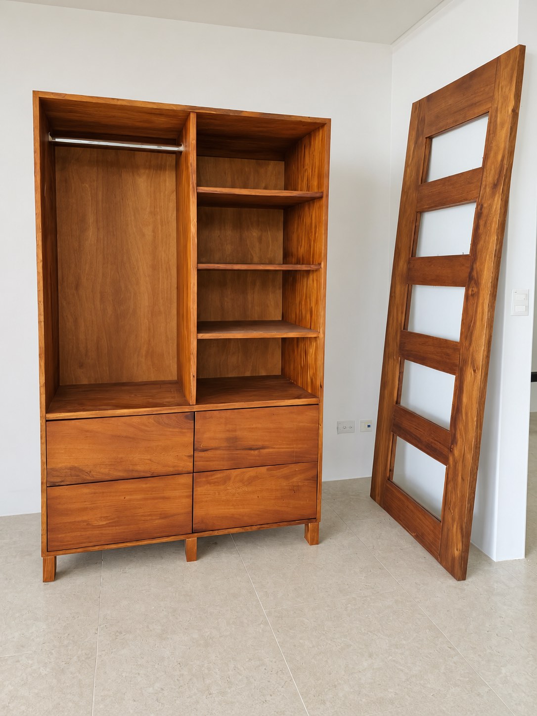 Closet de madera con gavetas junto a una puerta de madera y vidrio