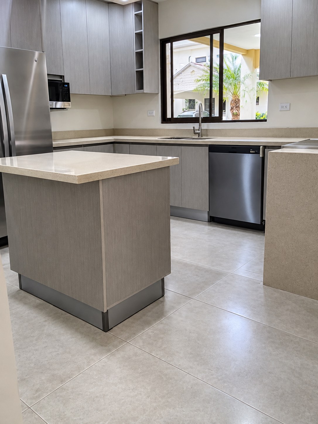 Cocina en gabinetes gris con isla y sobre de cuarzo